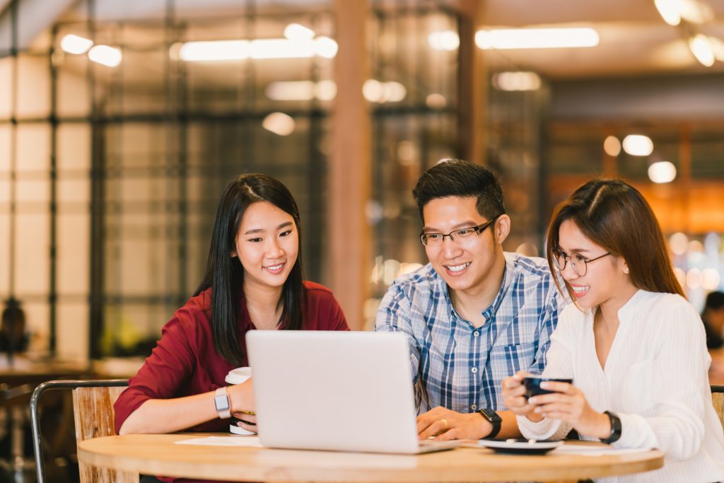 group of asian men and women looking at a laptop screen