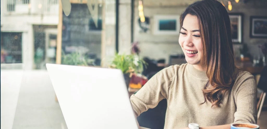 happy young asian woman looking at her laptop