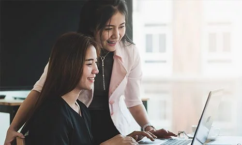 two asian women looking at a laptop screen