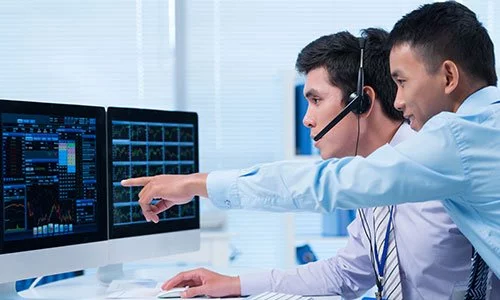 two asian men talking while looking at a computer screen