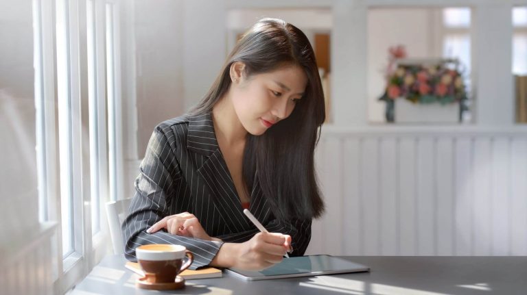 asian woman having coffee and using her tablet