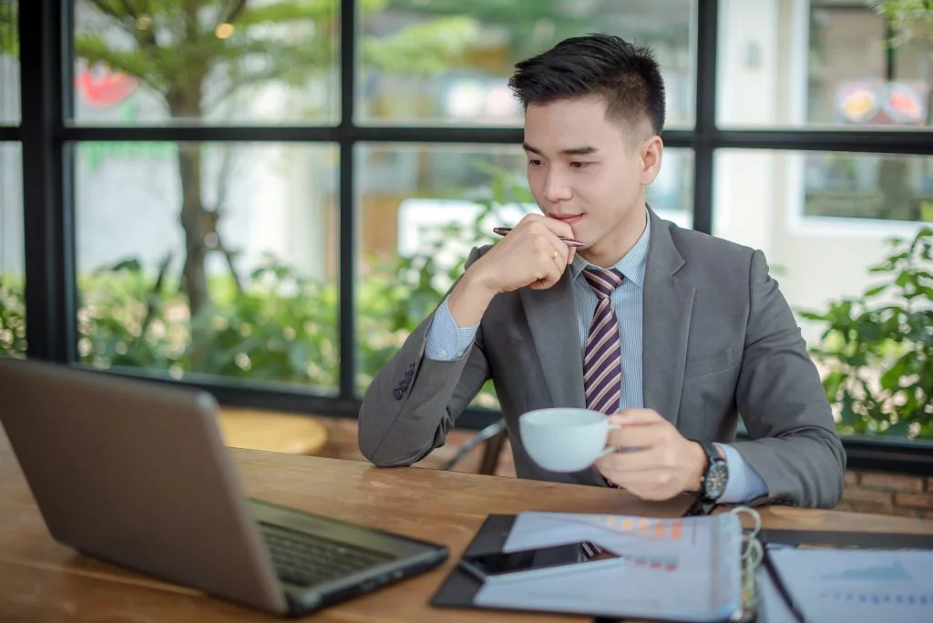 Man looking at laptop while holding his coffee