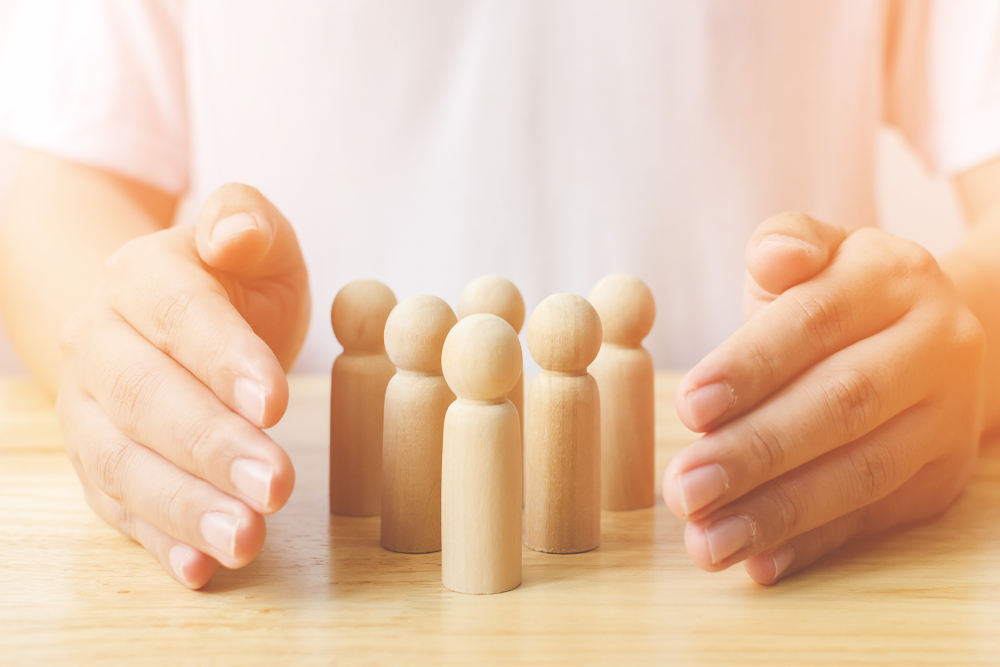 hands encircling human wooden pegs portraying good management