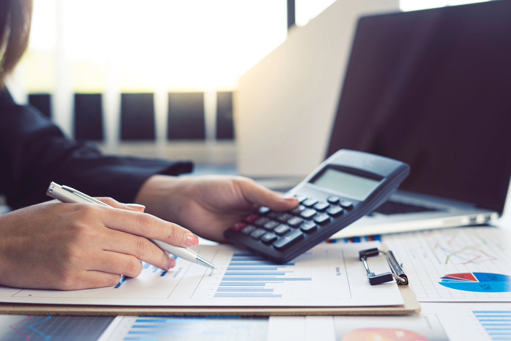 woman using a calculator while analayzing financial documents