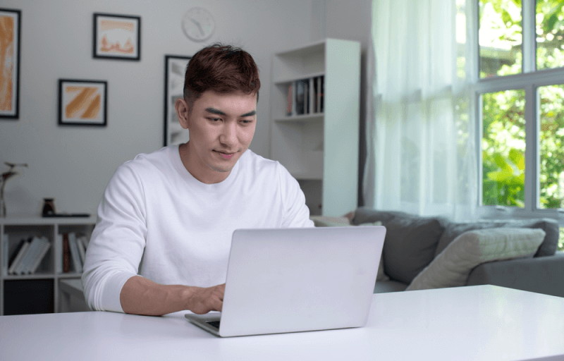 young asian man at home using his laptop