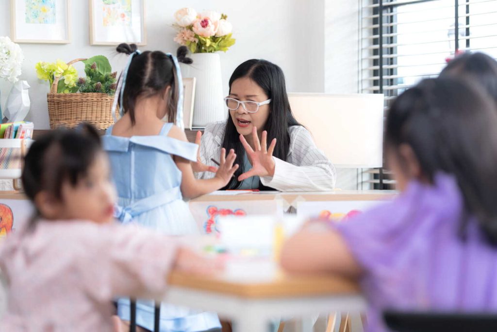A teacher engages young children in an interactive activity at a classroom table